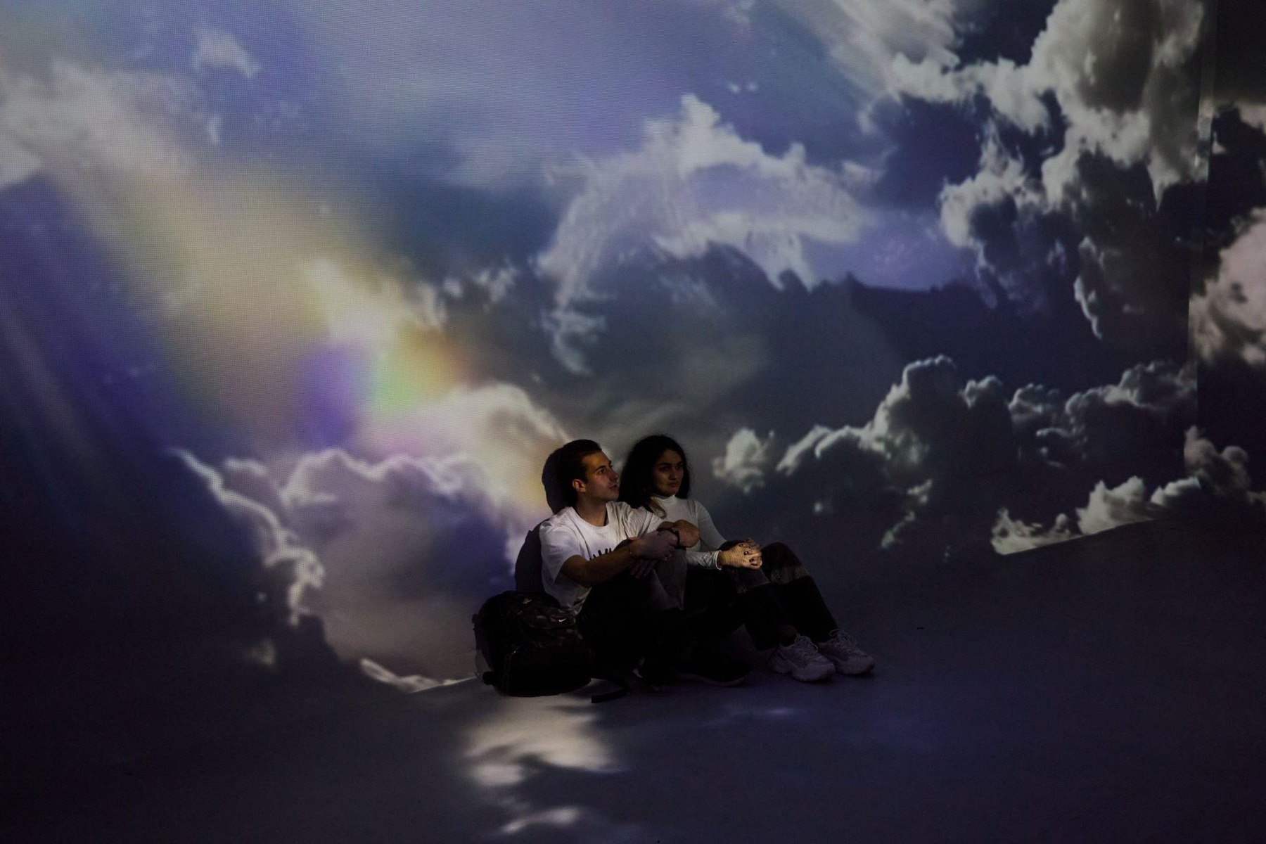 Immersive projection of clouds with performers in silhouette.