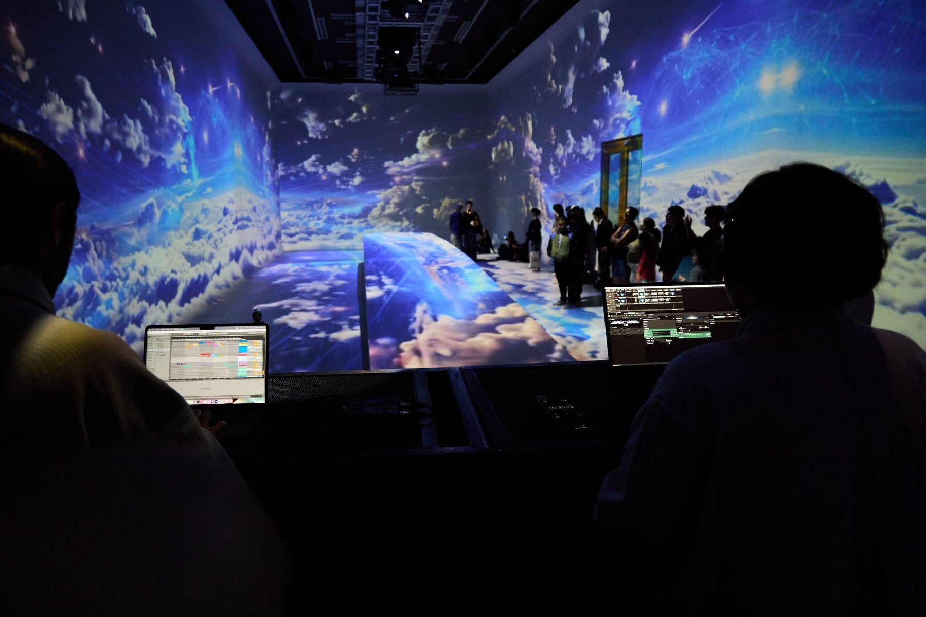 Audience facing a large immersive audiovisual projection.